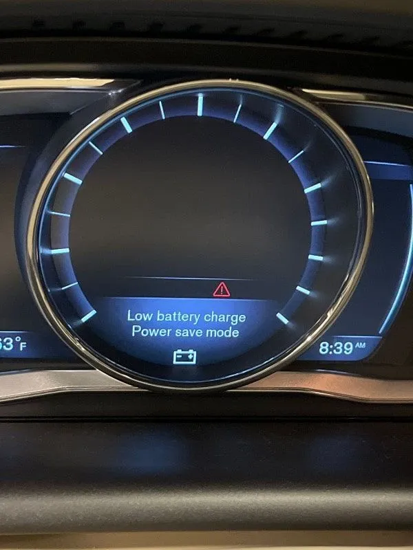 A car dashboard in San Antonio displays Low battery charge. Power save mode warning message at 8:39 AM, marking a moment in the vehicle’s history.